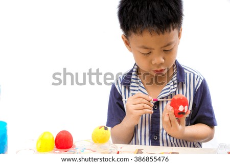 Asian boy painting on Easter eggs on white background with space