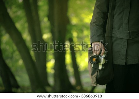 Hipster female photographer exploring spring nature landscapes and making photos of beautiful season scenery with generic vintage film camera, selective focus on hand holding photo equipment.