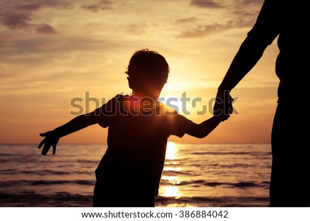 Father and son playing on the beach at the sunset time. Concept of happy friendly family.