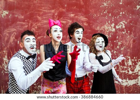 Four mimes looking aside on the background of a red wall. Royalty-Free Stock Photo #386884660