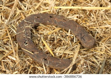 Rusty horseshoe on a straw background - rustic scene in a country style. Old iron Horseshoe - good luck symbol and mascot of well-being in a village house in Western culture.
