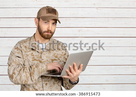 Portrait of young army soldier with a laptop