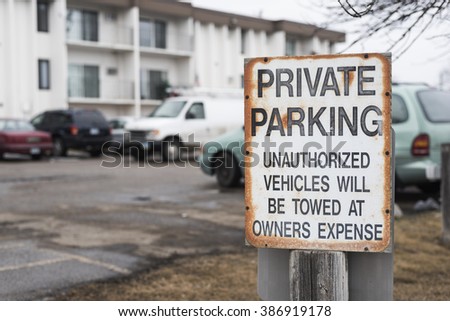 old, rusty private parking sign stating unauthorized vehicles will be towed at owners expense. 