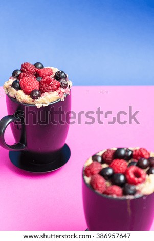 Mug Cakes with Berries Prepared in Microwave on Pink and Blue Funny Background, Vertical View