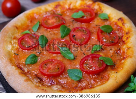 Italian cuisine. Mediterranean cuisine. Pizza Margherita with tomato topped with melted golden cheese, herbs and basil served  on old wooden table