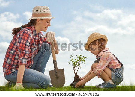 Mom and her child girl plant sapling tree. Spring concept, nature and care. Royalty-Free Stock Photo #386990182