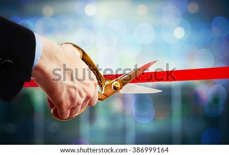 Businessman cutting red ribbon with pair of scissors close up Royalty-Free Stock Photo #386999164