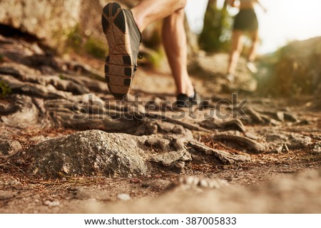 Cross country running. Closeup of male feet run through rocky terrain. Focus on shoes. Royalty-Free Stock Photo #387005833