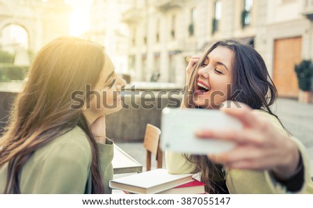 Two young women taking selfie with smart phone in the city center. Happiness concept about people and technology