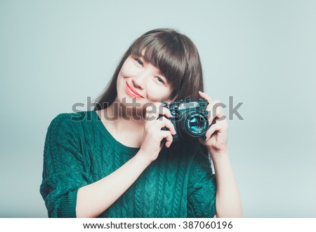 Portrait of a young woman taking pictures on the retro, vintage camera, isolated on gray background