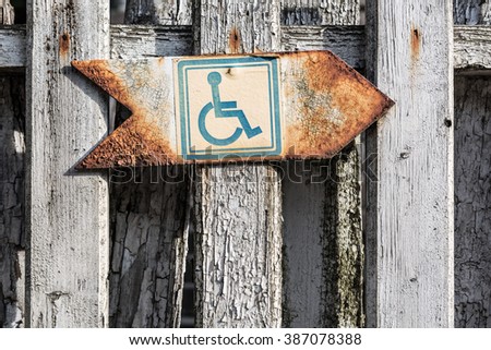 Disability sign on old rusty board, symbol of handicapped. Man on wheelchair sign.