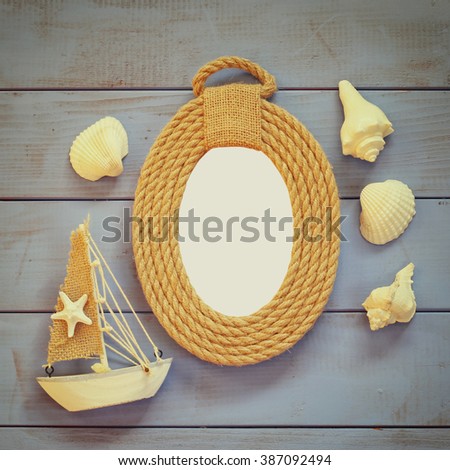 wooden ropes frame, lighthouse and sailing boat on wooden table. nautical lifestyle concept. vintage filtered and toned. template, ready to put photography
