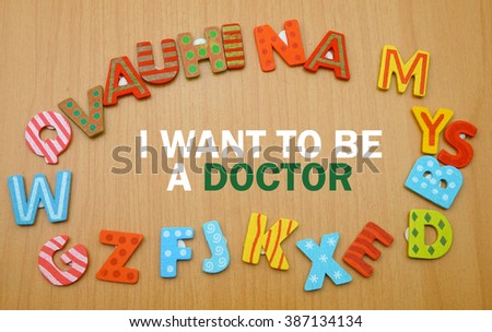 A word "i want to be a doctor" in a circle of alphabet letter with the wood background. copy space                        
