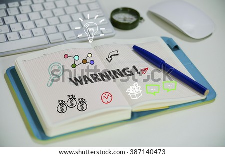 drawing WARNING concept on notebook in the office , business concept , business idea, analysis concept