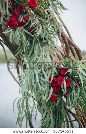 Wedding. Ceremony. Wedding arch. Wedding arch made of branches, flowers and greenery is on the green grass on the river bank