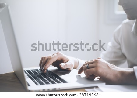 Close up of young businessman working at his office on laptop, male hands using modern notebook computer in interior