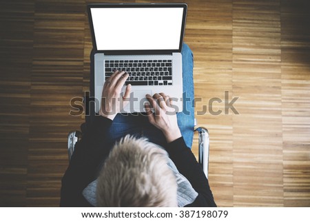 Top view of young man sitting at home and using laptop with blank screen for your content, closeup of businessman typing on laptop keyboard at comfortable interior, freelancer working on computer