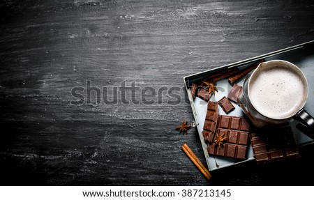 Hot chocolate with cinnamon and bitter chocolate. On black rustic background.