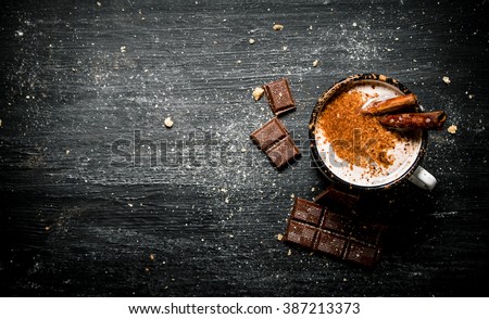 Aromatic cocoa drink with cinnamon and chocolate. On black rustic background