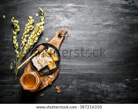Honey background. Natural honey and herbs on a wooden Board. On black rustic background.