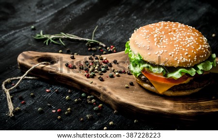 A hamburger on a wooden Board. On a black chalkboard. 