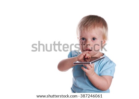 Happy little baby surprised in a blue t-shirt plays with mobile phone, isolated on a white, studio shot