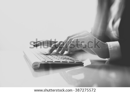 Closeup photo of female hands typing text on a wireless keyboard. Business woman working at the office. Visual effects, black white