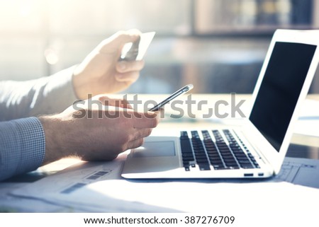 Photo businessman working with generic design notebook smartphone. Online payments credit card, texting keyboard. Blurred background, film effect. Horizontal