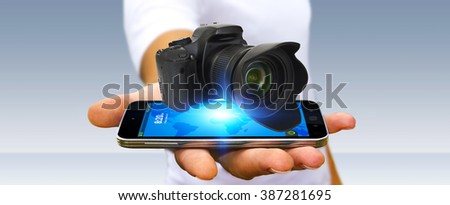 Young man holding modern digital camera over his mobile phone