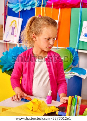 Female kid holding colored paper on table in kindergarten. Children's Art Class.
