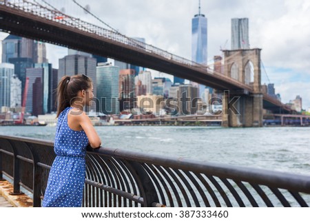 New York city urban woman enjoying view of Brooklyn bridge and NYC skyline living a happy lifestyle walking during summer travel in USA. Female Asian tourist in her 20s.
