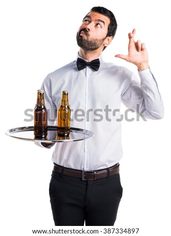 Waiter with beer bottles on the tray with his fingers crossing