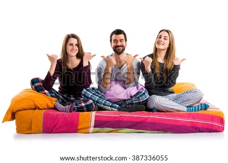 Three friends on a bed with thumb up