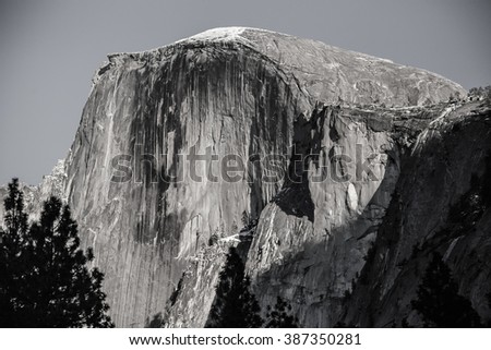 November afternoon sunlight illuminates Half Dome in Yosemite National Park, California. Color original is converted to black and white with film grain effect to simulate an old-time analog picture.