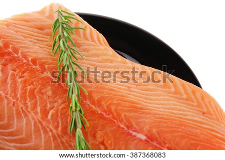 raw fresh uncooked salmon red fish fillet on black plate with rosemary twig isolated over white background