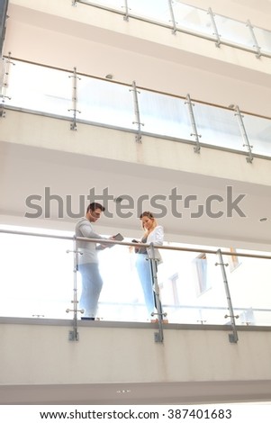Business partners talking in corridor of multi-storey building.