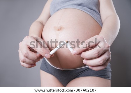 Pregnant woman quits smoking. Studio shot on a gray background. Health care concept