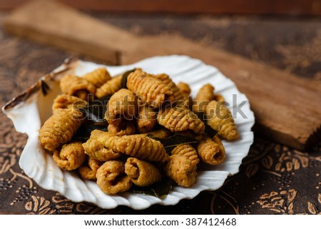 vintage rustic shot of traditional homemade kuih siput deep fried biscuit cookies in the shape of snails on a shell platter normally served during festivals likeramadhan and lunar chinese new year