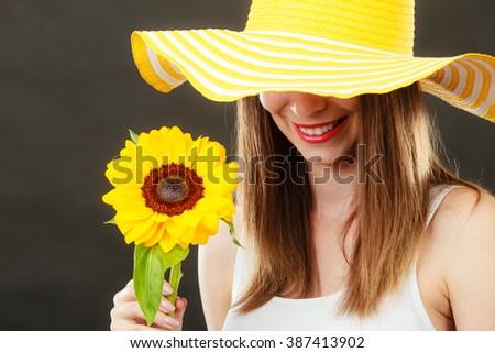 Portrait of attractive summer woman in yellow hat with sunflower in hand on black background