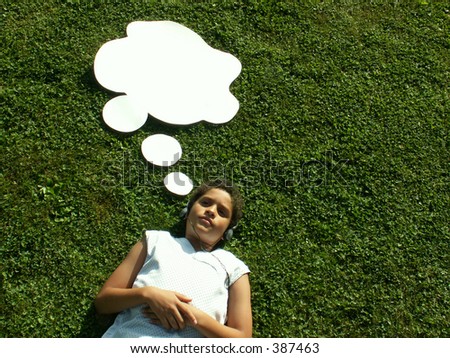 boy with headphones on lying in grass with blank cartoon thought bubble over head