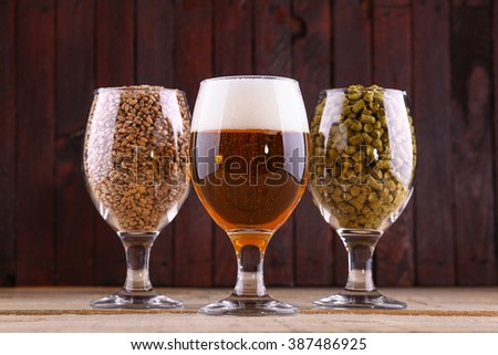 Glasses of beer, malt and hops over a wooden background Royalty-Free Stock Photo #387486925