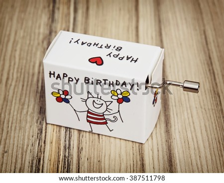 Music box with funny title happy birthday on the wooden background.