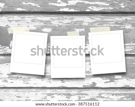 Close-up of three square photo frames with adhesive tape on monochrome scratched wooden boards background