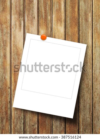 Close-up of one square photo frame with orange pin on brown vertical wooden boards background