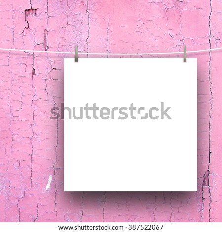 Close-up of one hanged square paper sheet frame with pegs on pink weathered wooden boards background