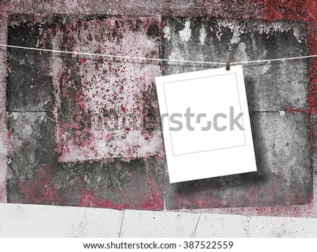 Close-up of one hanged square photo frame with peg on scratched wall background