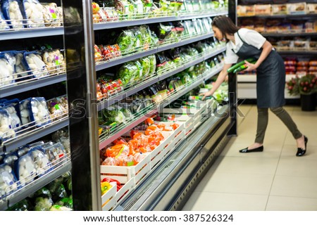 Portrait of a smiling worker taking a vegetables in supermarket