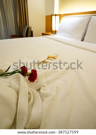 Elegant and comfortable home & hotel bedroom interior as background, the red carnation flowers and bath towel at bed, romantic style.