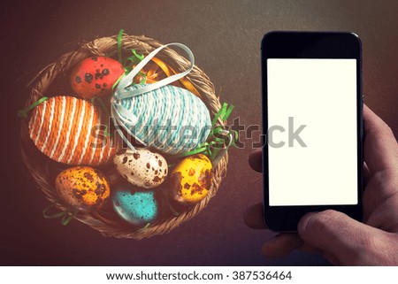 Colorful Easter eggs from above on dark background with blank space on smart phone screen