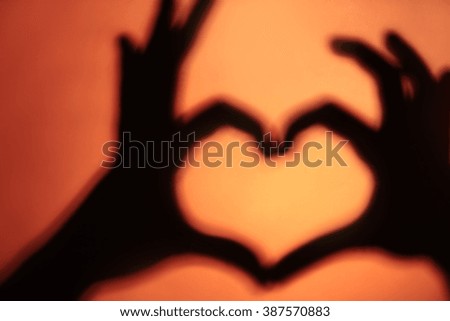 Hand shaped heart on orange background